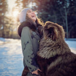 Little girl is playing with her dog in the snowy forest